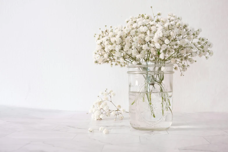 a vase with flowers and water sitting on top of a table