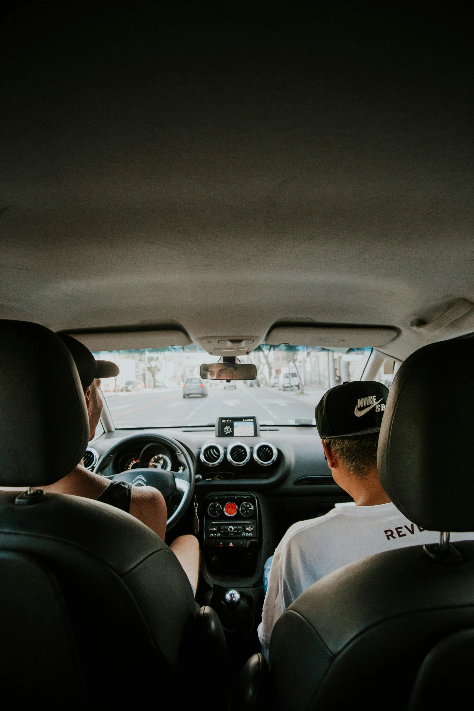 two men drive a car while talking to each other