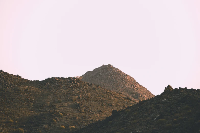 a mountain side with some brown grass on the hillside