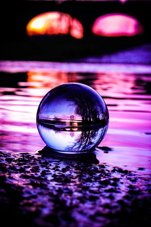 a close up of a shiny ball of liquid near a pond