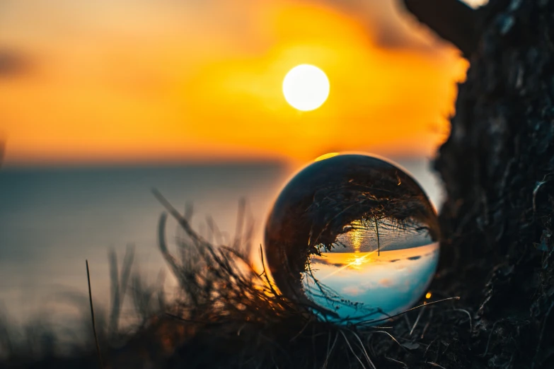 the sunset is reflected in the shiny marble ball