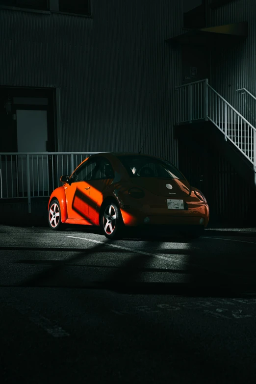 a bright orange car is parked in a parking lot at night