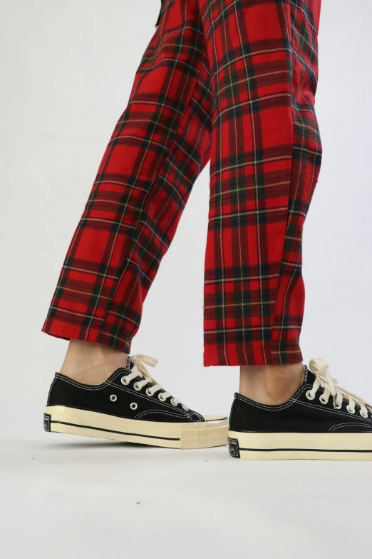 a person wearing plaid pants and converse sneakers