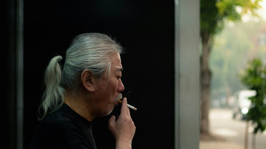 an older man smoking a cigarette in front of a door