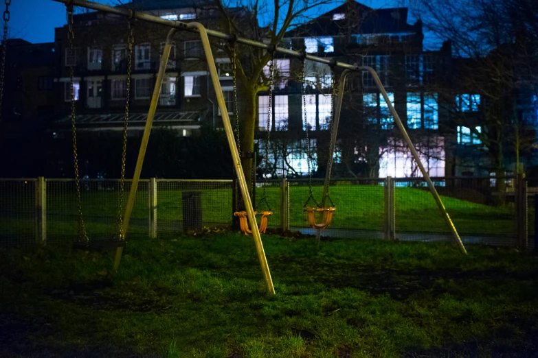 a wooden swing sits in the grass at night