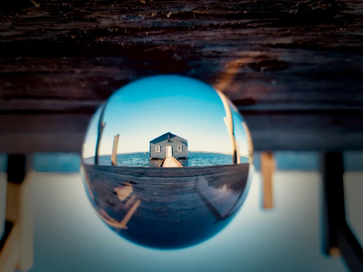 a boat house seen in a mirror on the ocean