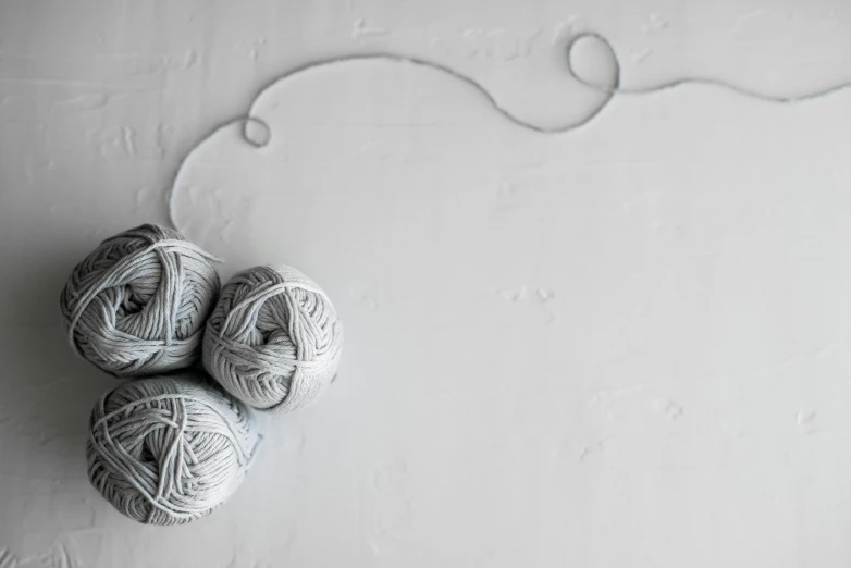 three balls of yarn sit in the middle of a white wall