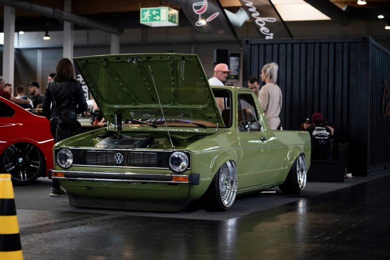 a green truck with the hood open at a car show