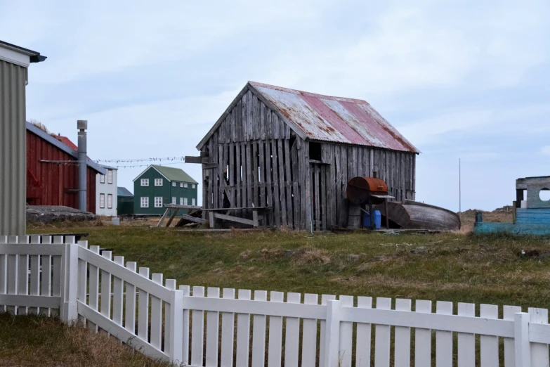 an old abandoned house in a grassy field with a white fence and a blue pickup truck