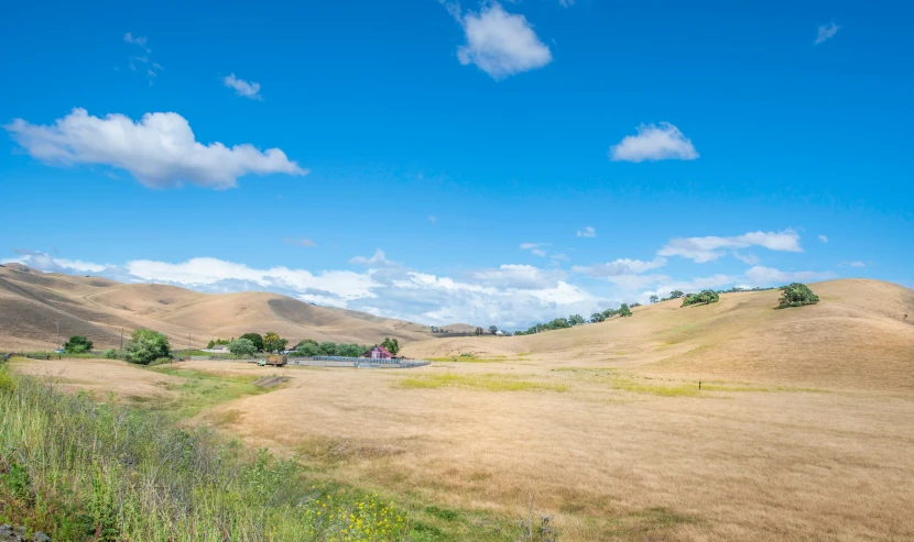 some brown hills and houses in a grassy area