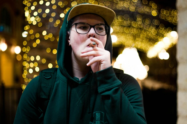 a young man with glasses smoking a cigarette