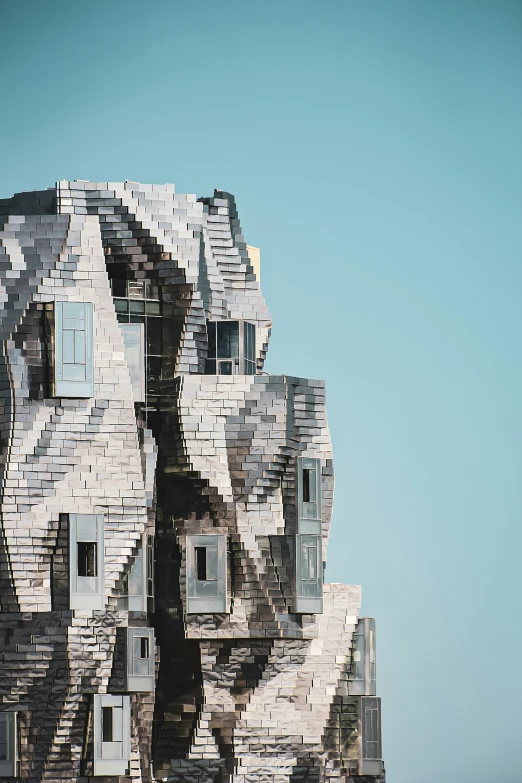 an unusual shaped sculpture by the sea against a blue sky