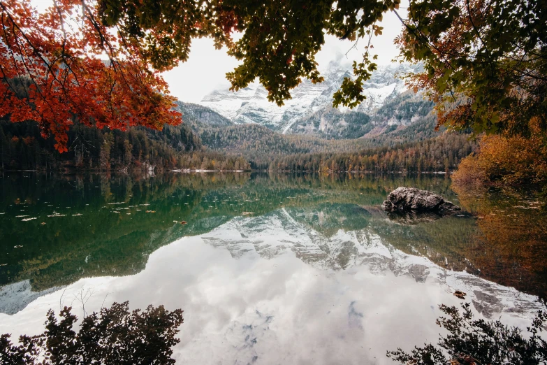 a lake surrounded by mountains with water reflecting the sky