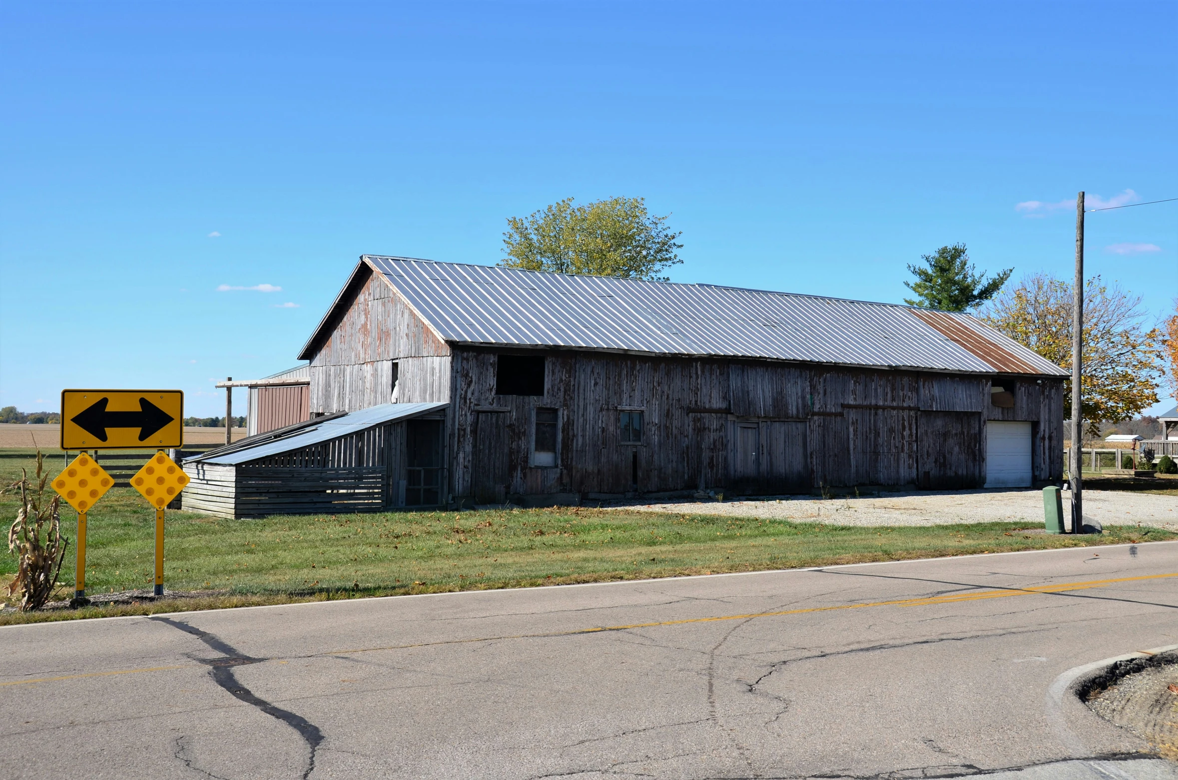 an old barn sits near the side of a country road