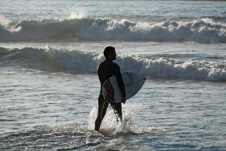 a person walking in the ocean with their surf board