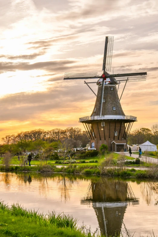 a large windmill on top of grass next to a river