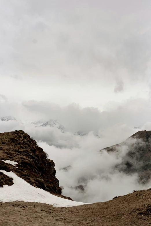 two skiers going uphill while clouds fly low