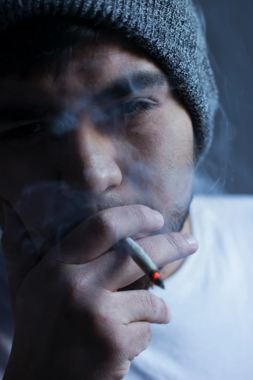a man smoking a cigarette wearing a beanie