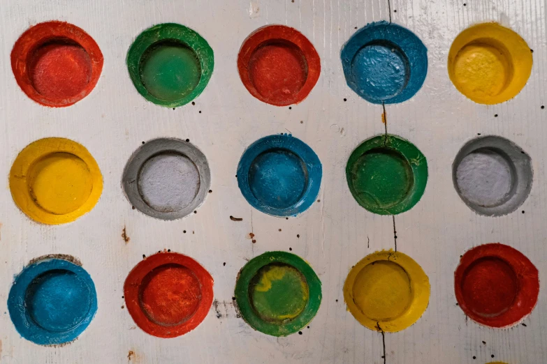 many paint circles in multicolored hues sitting on a white surface