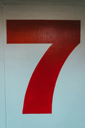 the number seven is painted in red on a light blue wall