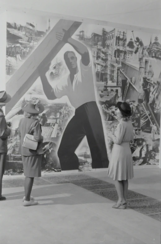 a couple of women standing next to a giant painting