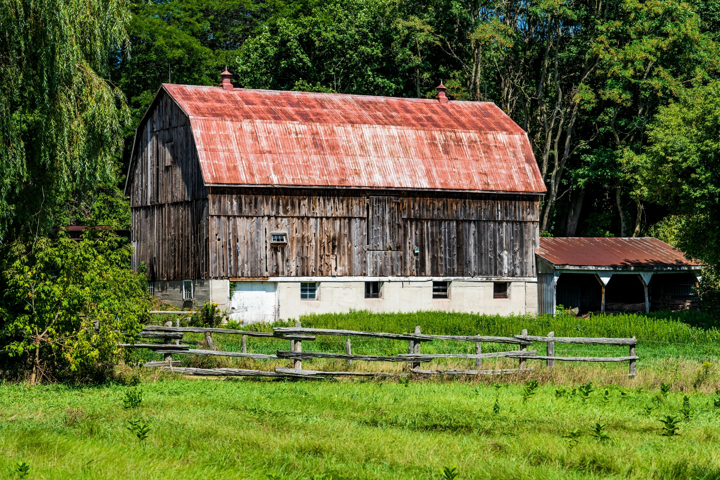an old building is sitting in a field near trees