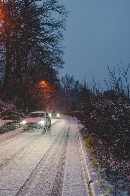 cars are parked along the side of a snow covered road