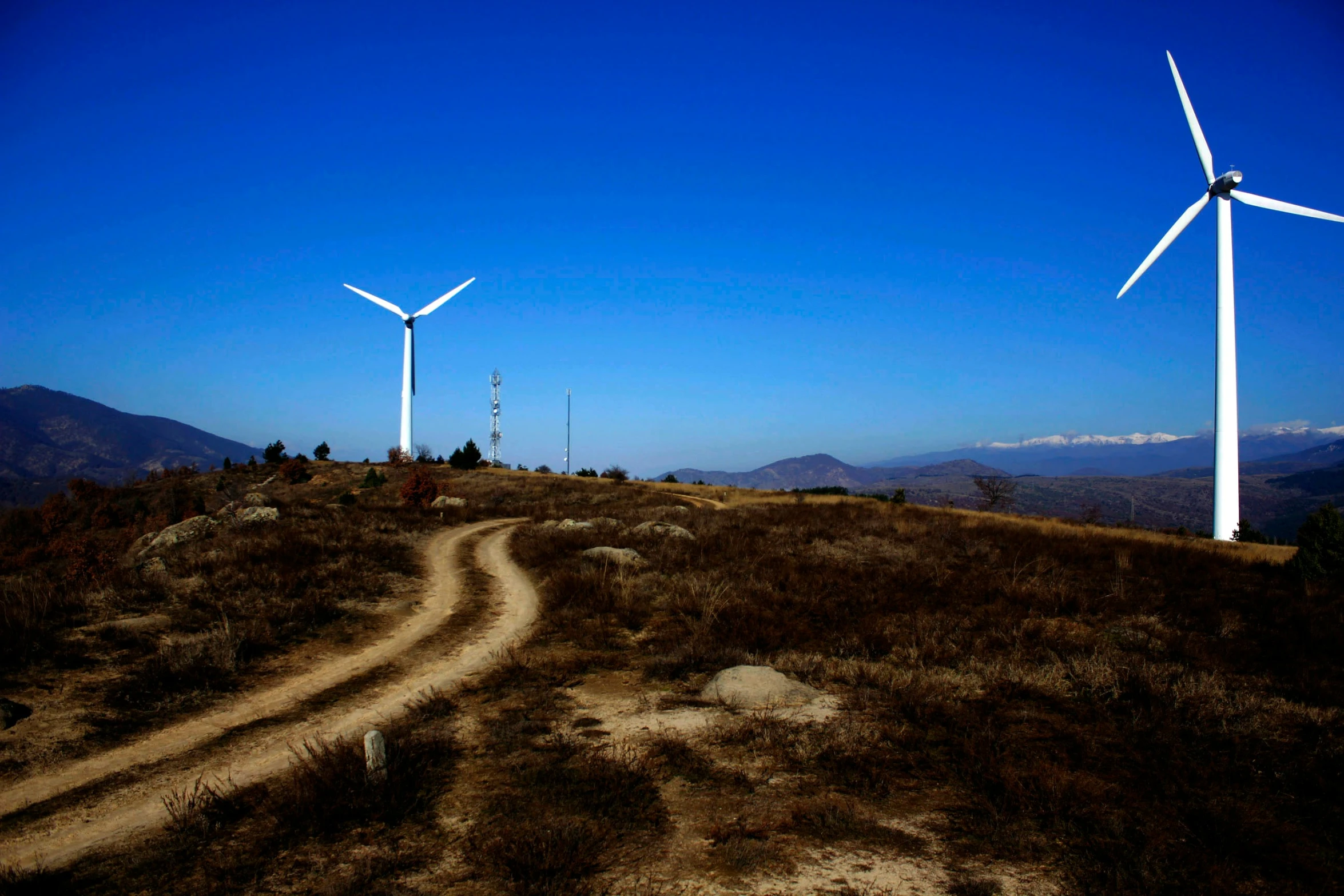 a dirt road and several wind turbines in the background