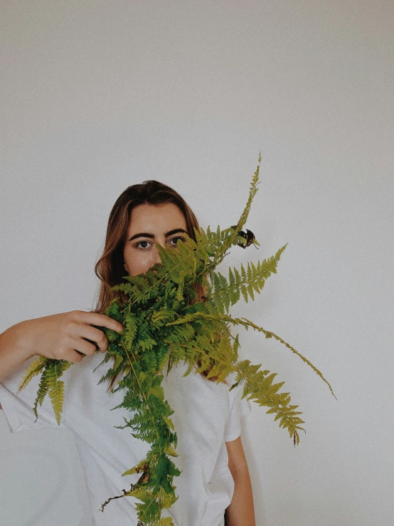 a person holding up a plant over their face