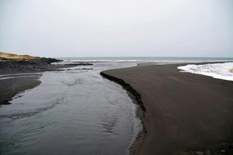 an empty beach is covered in snow and some water