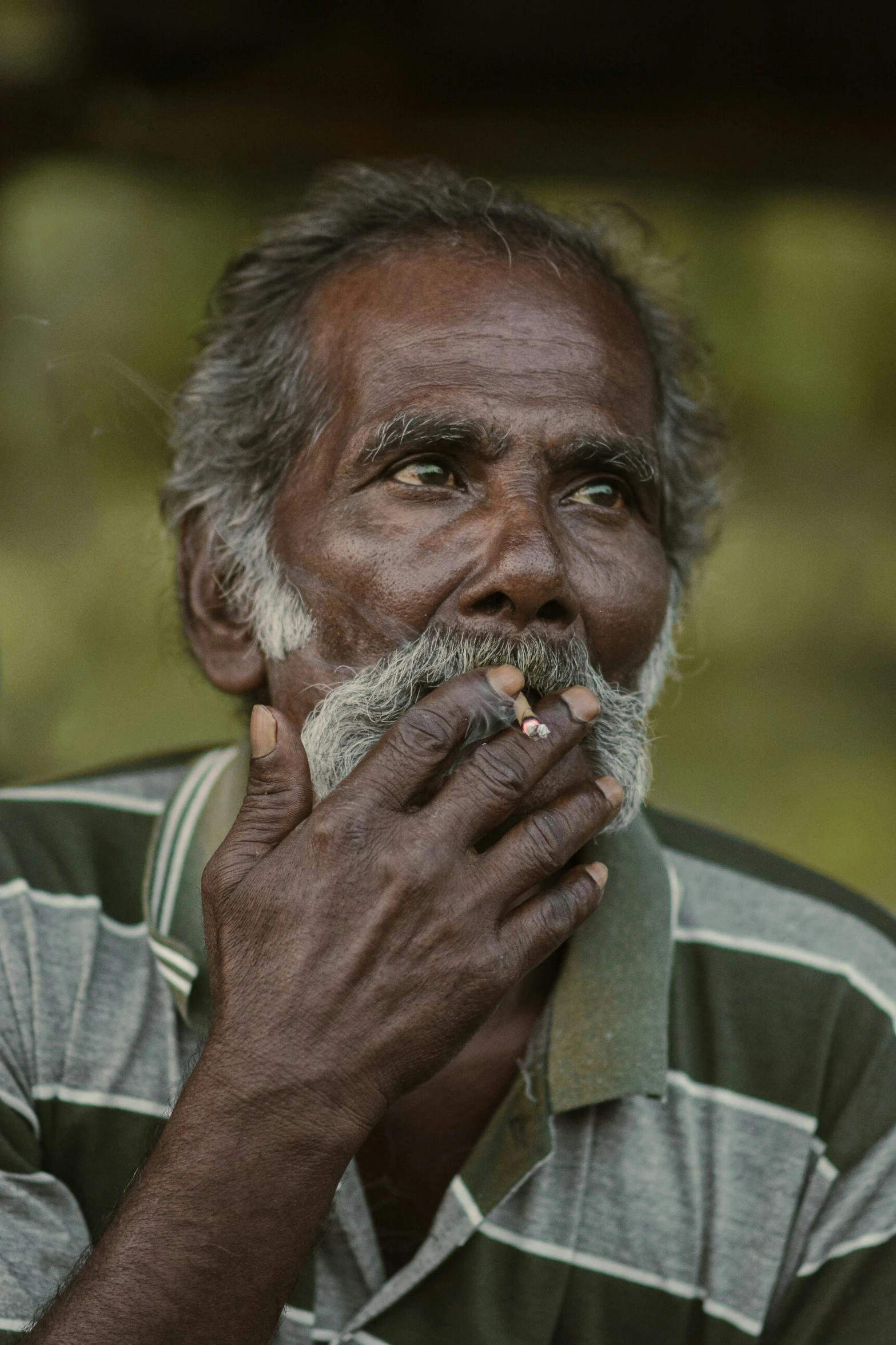 a man that is sitting down with his hand near his mouth