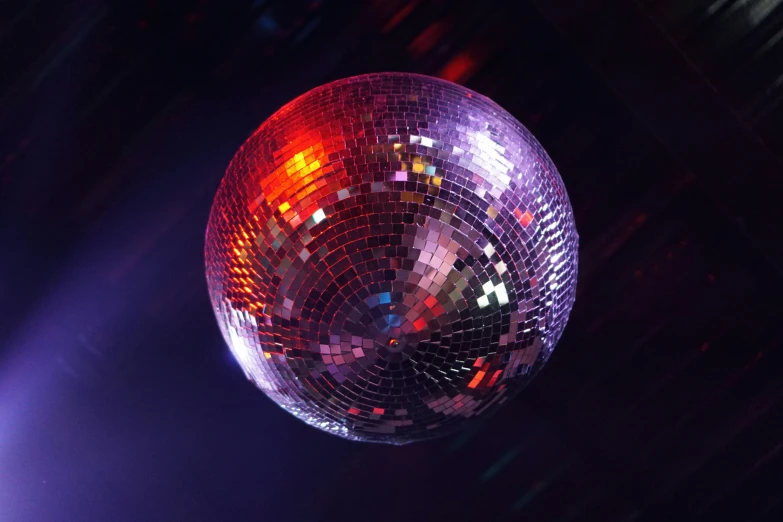 a disco ball lit up by lights on top of a stage