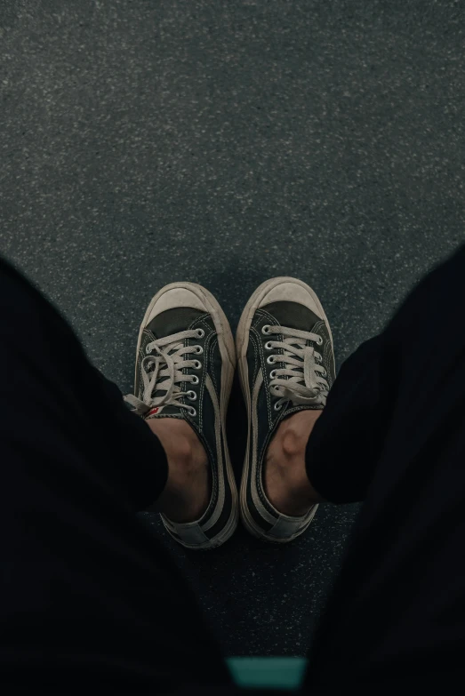 an aerial view of two persons'feet and one has their green sneakers on