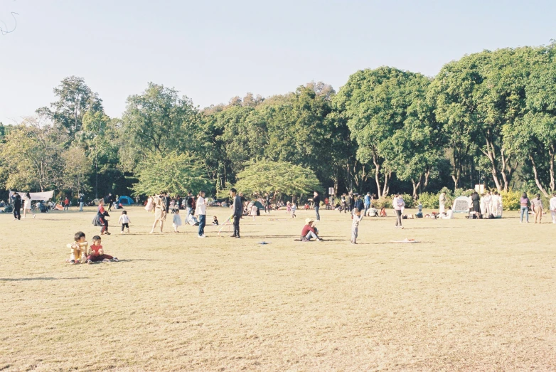 a park that is filled with lots of people playing with a kite