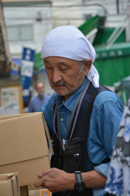 an elderly man carrying cardboard boxes in front of a truck