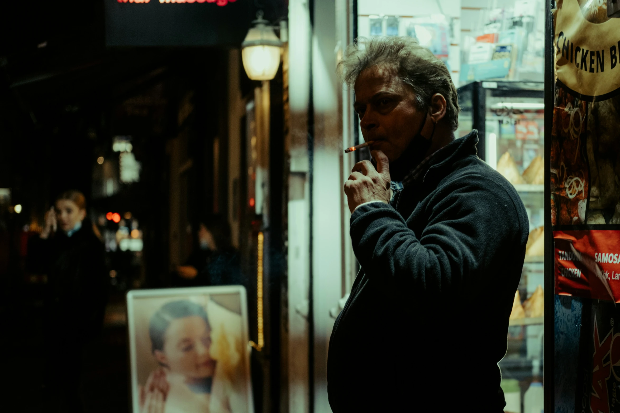 a man is standing outside with a cigarette in his hand