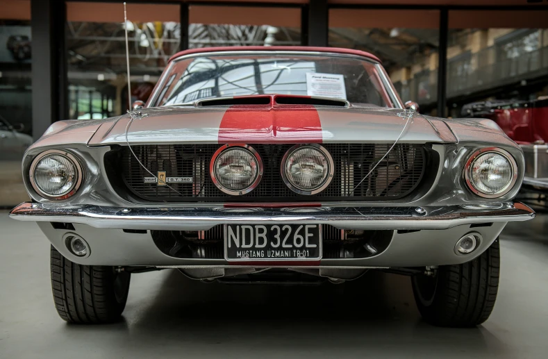 an older mustang with stripes and headlights in a garage