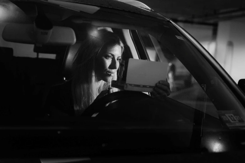 woman sitting in a car holding a piece of paper