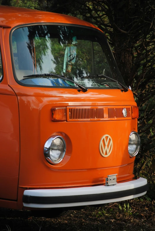 an orange vw bus parked in front of a bush