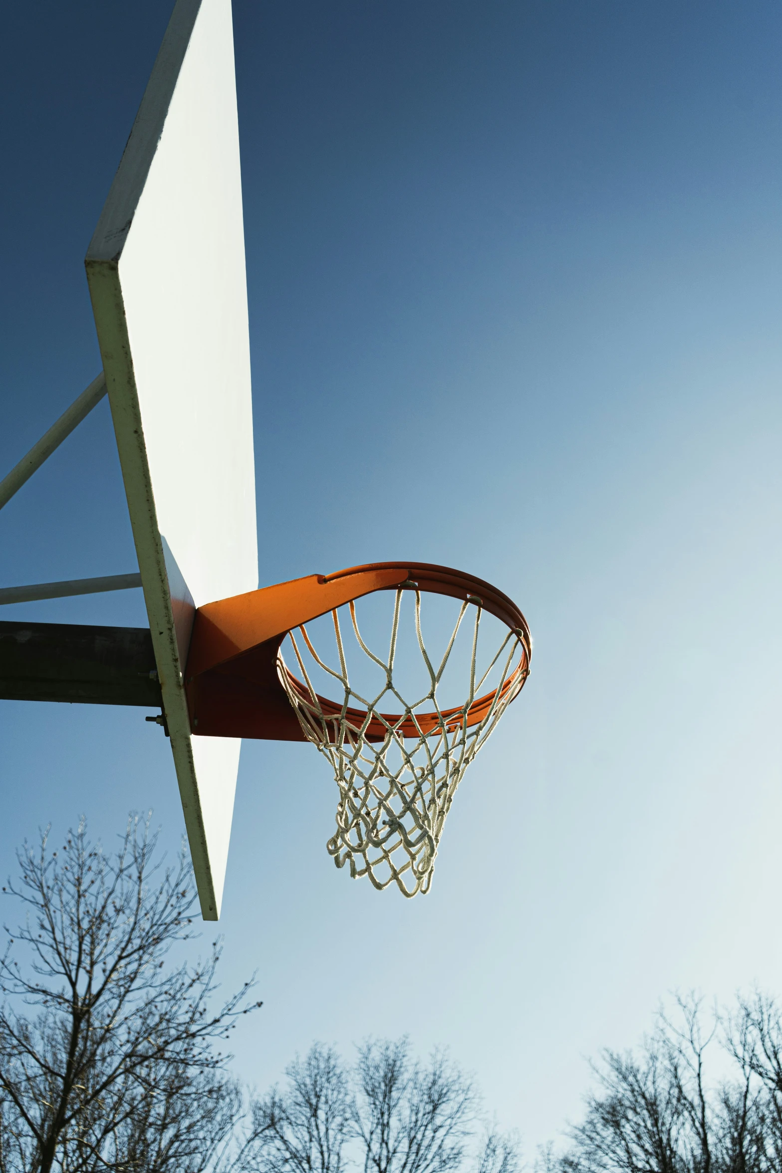 a basketball going through a basketball court with trees in the background