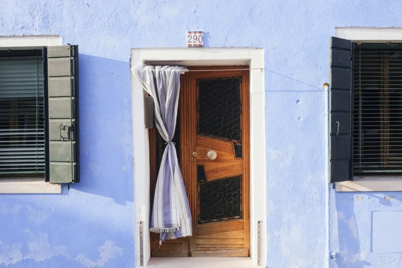 a blue wall with two windows and a striped curtain