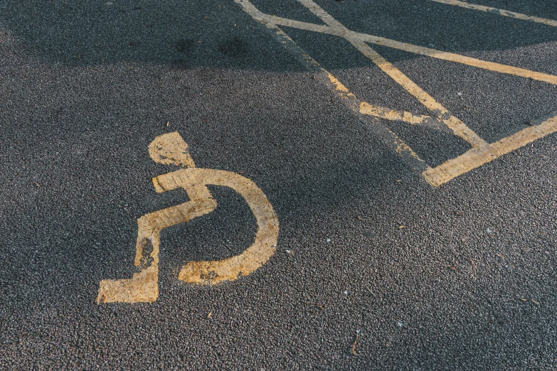 a handicapped sign on asphalt next to an underpass