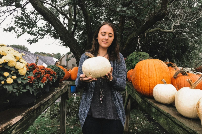 a woman is holding pumpkins on a set of wooden crates