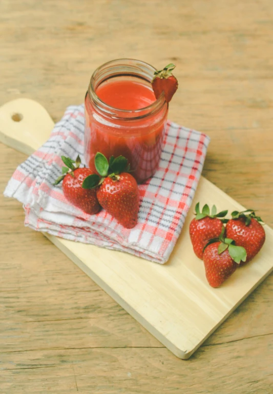 strawberry jam on a towel next to two small strawberries