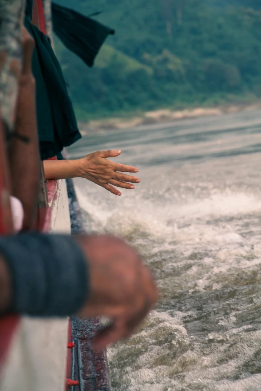 a man holding his hand out towards a boat on choppy water