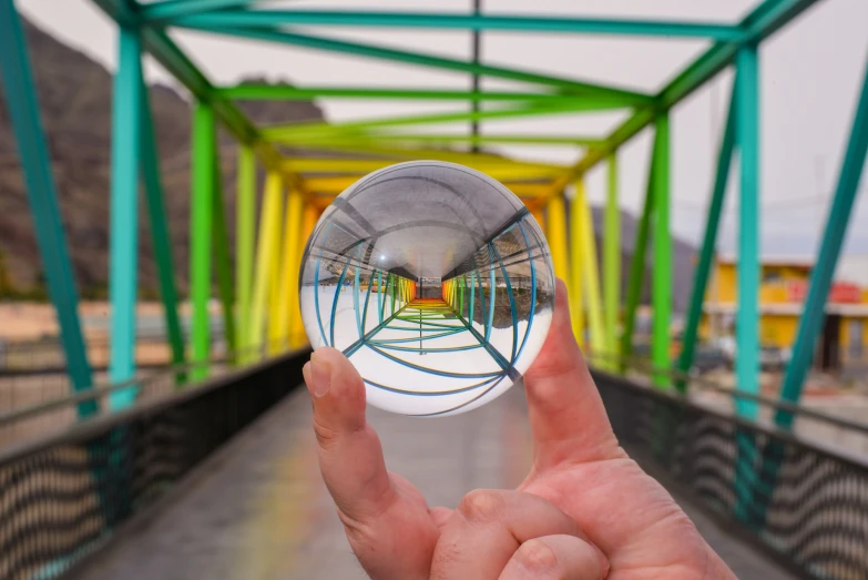 someone is holding a small object on a bridge