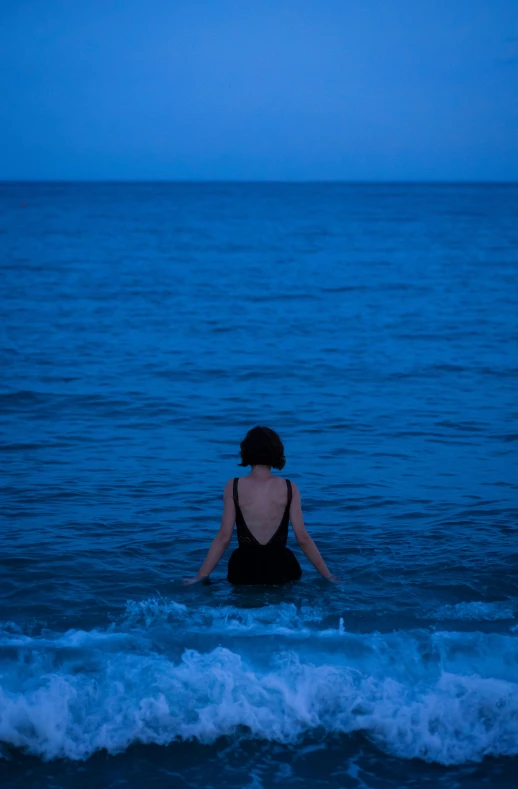 a person standing in the water with their back turned