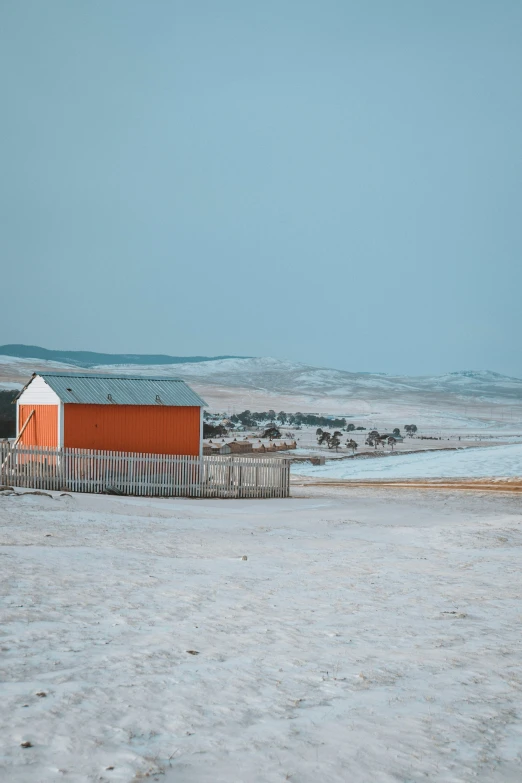 a beach with a fenced in area, with a red building and a white building