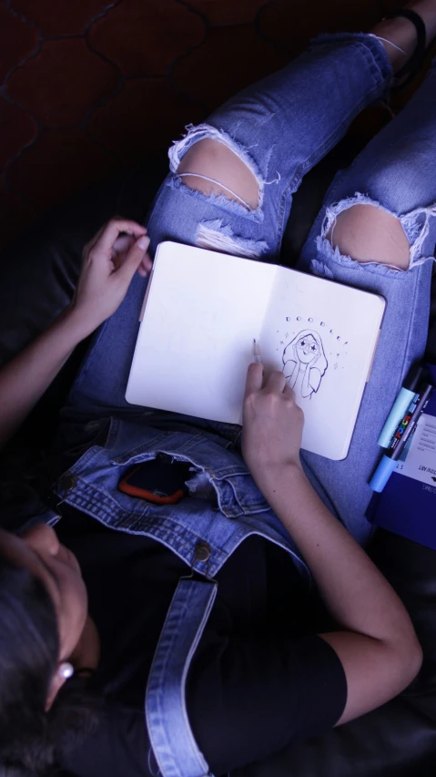 a girl in a pair of ripped jeans writing with a tablet