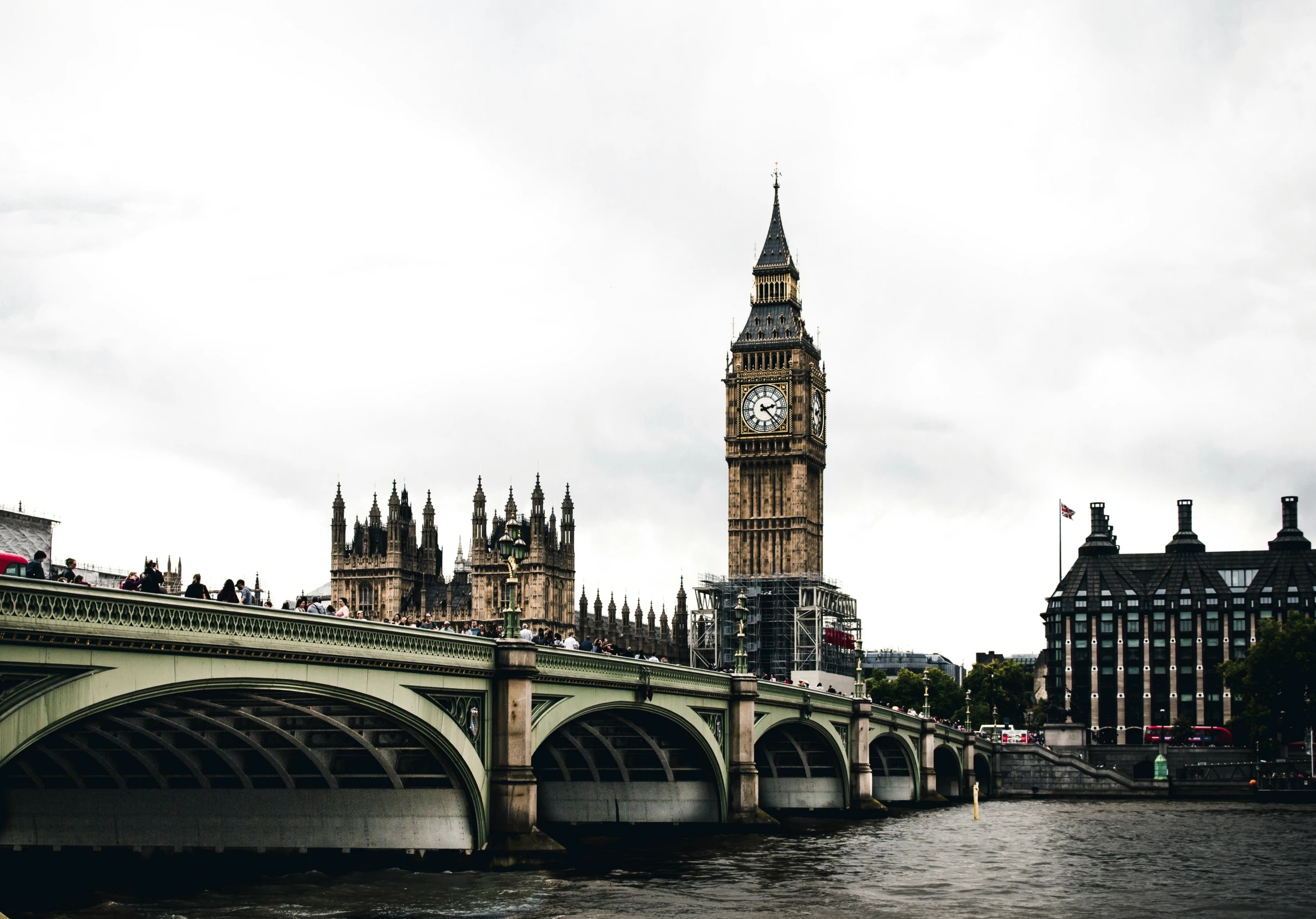 big ben stands behind the bridge and buildings on the other side